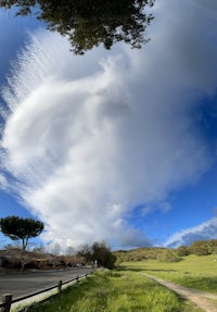 a cloudy sky over a grassy field